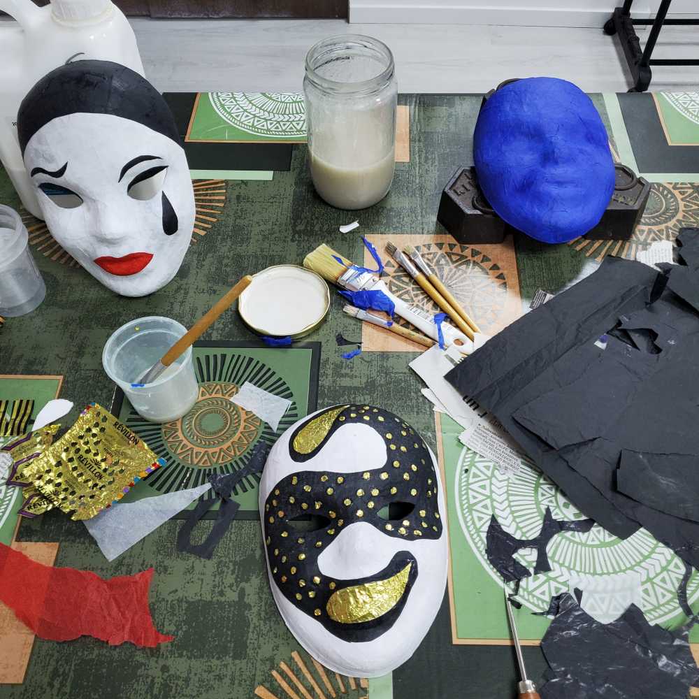 trois masques en papier mâché en cours de création dont un masque de Pierrot