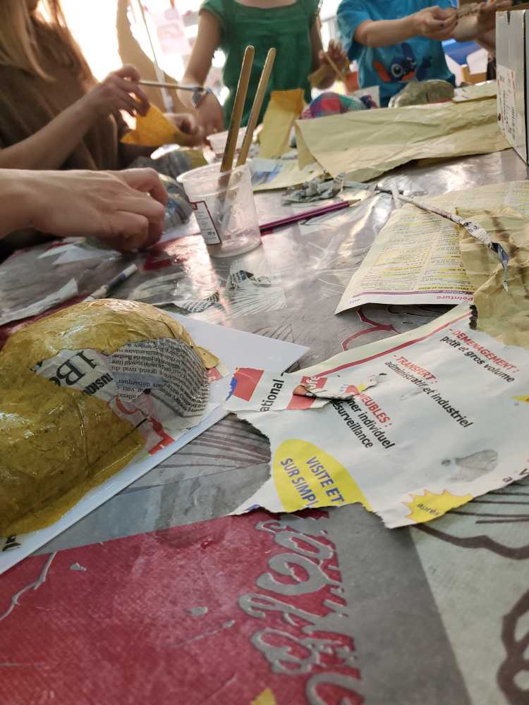 finition du masque en papier mâché avec du papier kraft pour donner l'impression d'un masque en argile